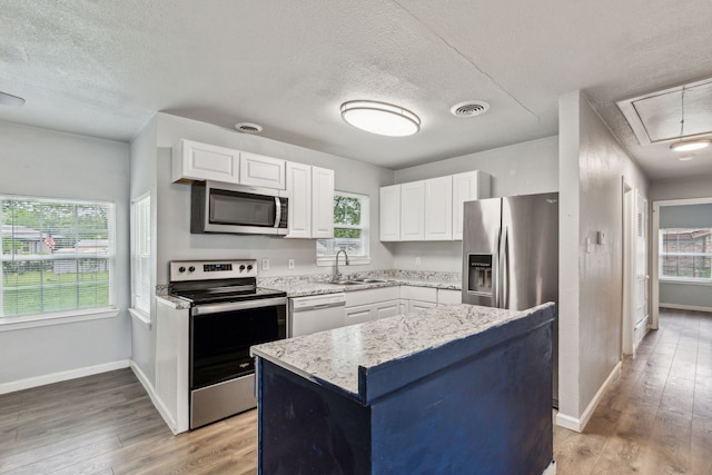 5225 Ira St N, Haltom City, TX 76117 - kitchen featuring stainless steel appliances, a textured ceiling, a sink, white cabinets, and baseboards