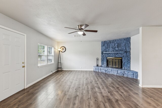 5225 Ira St N, Haltom City, TX 76117 - unfurnished living room with wood finished floors, a ceiling fan, a textured ceiling, a stone fireplace, and baseboards