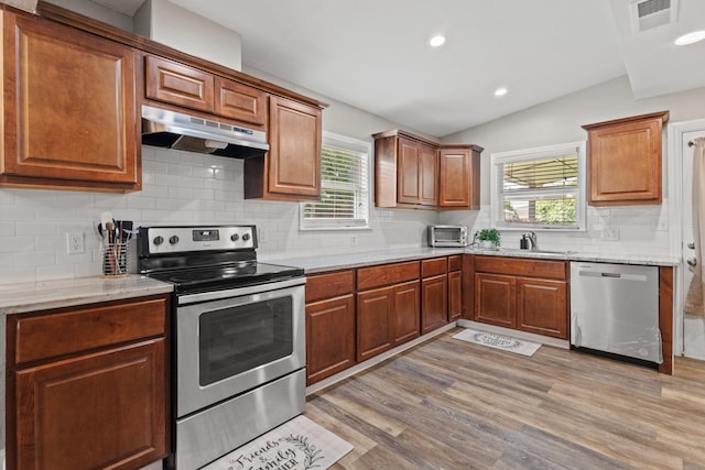 3607 Cortez Dr, Dallas, TX 75220 - kitchen with appliances with stainless steel finishes, under cabinet range hood, a sink, vaulted ceiling, and light wood-style floors
