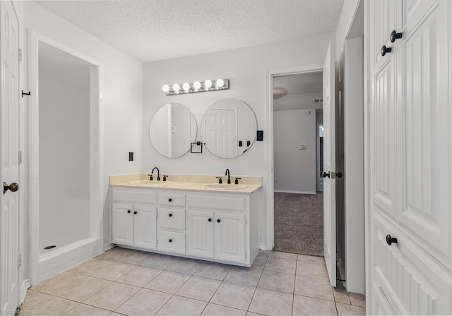 2810 Live Oak Dr, Rowlett, TX 75088 - bathroom with a textured ceiling, tile patterned flooring, double vanity, and a tile shower