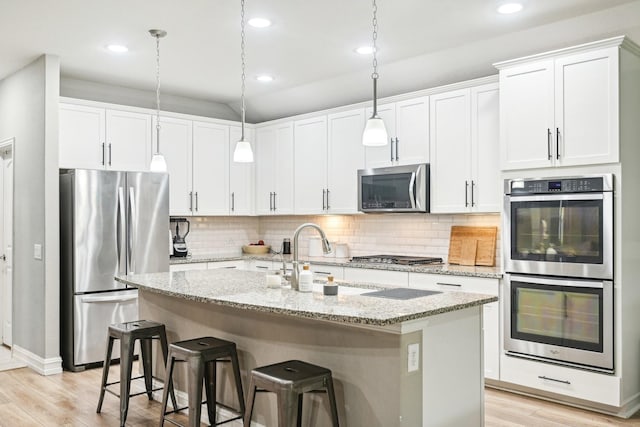 3613 Texas Dall Ct, Mckinney, TX 75071 - kitchen with appliances with stainless steel finishes, light wood-style flooring, decorative backsplash, an island with sink, and recessed lighting