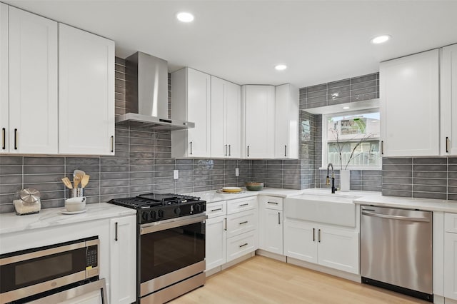 1425 Cassandra Cir, Desoto, TX 75115 - kitchen with appliances with stainless steel finishes, wall chimney range hood, a sink, light wood-style flooring, and light stone counters