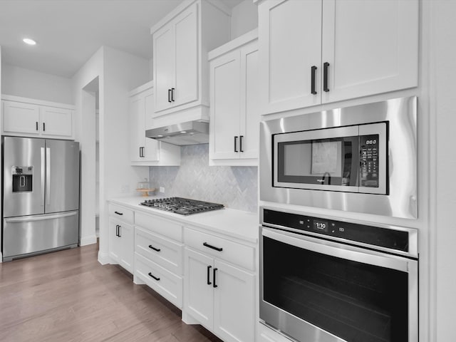 8620 Bandon Dunes Dr, Mckinney, TX 75070 - kitchen with stainless steel appliances, white cabinetry, light countertops, exhaust hood, and recessed lighting