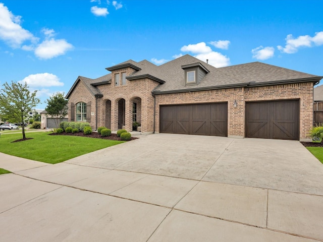 8620 Bandon Dunes Dr, Mckinney, TX 75070 - french country inspired facade featuring brick siding, an attached garage, a shingled roof, a front lawn, and concrete driveway
