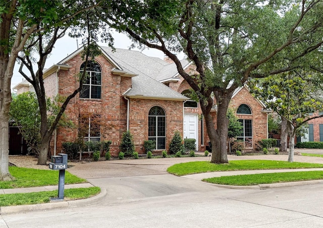7100 Deer Run, Plano, TX 75024 - traditional home featuring curved driveway, brick siding, and roof with shingles