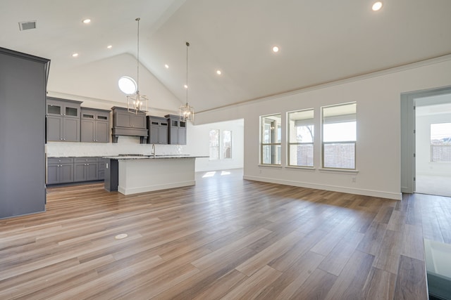 4005 Hollandwood Dr, Mckinney, TX 75071 - kitchen with gray cabinetry, open floor plan, glass insert cabinets, high vaulted ceiling, and a kitchen island with sink