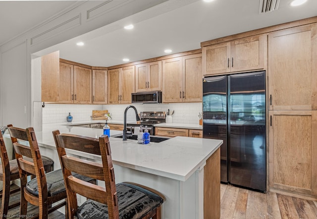 2012 Island Cir, Tool, TX 75143 - kitchen with appliances with stainless steel finishes, light wood-style floors, tasteful backsplash, a kitchen bar, and light stone countertops