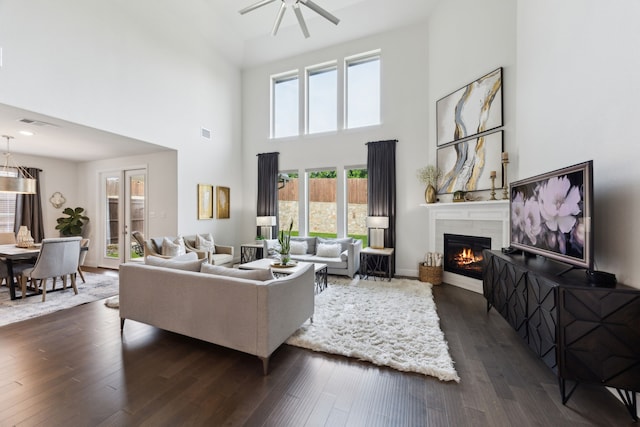 14326 Sedgegrass Dr, Frisco, TX 75033 - living area with a glass covered fireplace, a towering ceiling, plenty of natural light, a ceiling fan, and dark wood-type flooring