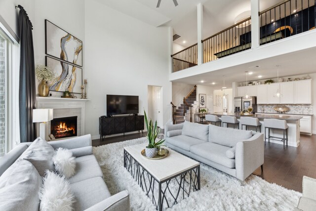 14326 Sedgegrass Dr, Frisco, TX 75033 - living room featuring stairs, dark wood-type flooring, a warm lit fireplace, and a high ceiling