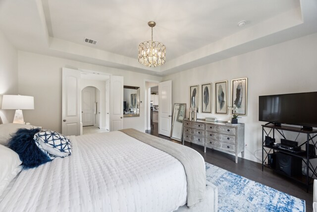 14326 Sedgegrass Dr, Frisco, TX 75033 - bedroom featuring a raised ceiling, a chandelier, wood finished floors, arched walkways, and baseboards