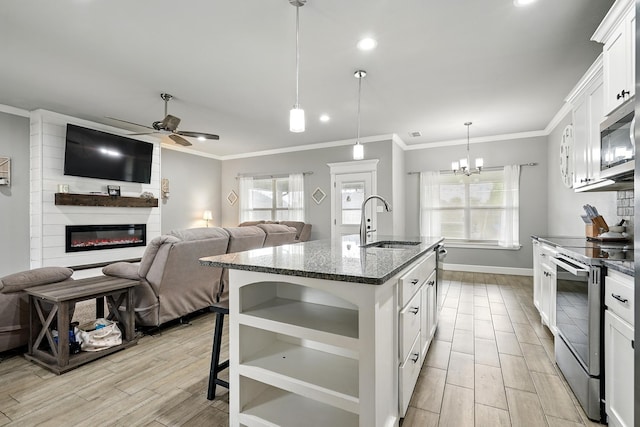 925 8th St, Tuscola, TX 79562 - kitchen with appliances with stainless steel finishes, a sink, a ceiling fan, a large fireplace, and wood tiled floors