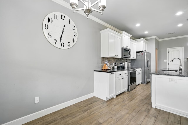 925 8th St, Tuscola, TX 79562 - kitchen featuring appliances with stainless steel finishes, a sink, crown molding, backsplash, and light wood-style flooring