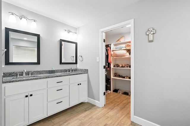 925 8th St, Tuscola, TX 79562 - bathroom featuring double vanity, wood finished floors, a walk in closet, and baseboards