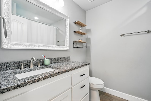 925 8th St, Tuscola, TX 79562 - full bath with vanity, toilet, baseboards, and wood finished floors