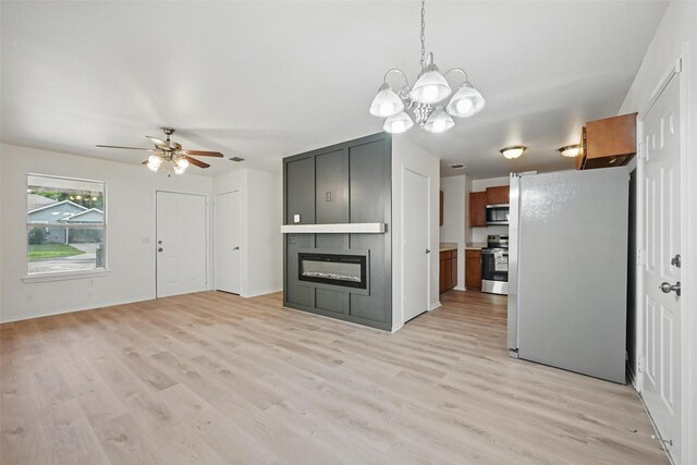 714 E 12th St, Bonham, TX 75418 - unfurnished living room featuring a chandelier, light wood-style flooring, a ceiling fan, and a fireplace