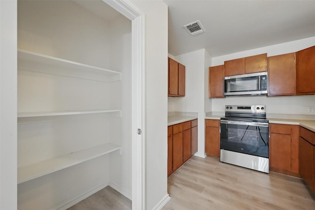 714 E 12th St, Bonham, TX 75418 - kitchen with appliances with stainless steel finishes, brown cabinets, and light wood-style floors