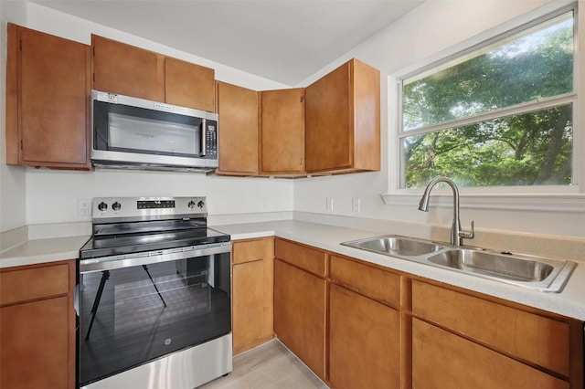 714 E 12th St, Bonham, TX 75418 - kitchen with appliances with stainless steel finishes, a sink, light countertops, and brown cabinets