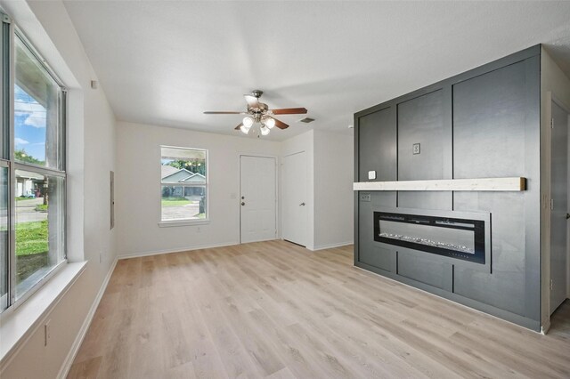 714 E 12th St, Bonham, TX 75418 - unfurnished living room featuring a large fireplace, light wood finished floors, a ceiling fan, and baseboards