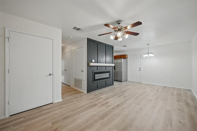 714 E 12th St, Bonham, TX 75418 - unfurnished living room featuring ceiling fan, a chandelier, light wood-type flooring, and baseboards