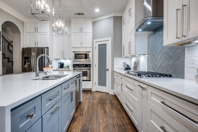 8230 Carter St, Lantana, TX 76226 - kitchen featuring appliances with stainless steel finishes, wall chimney exhaust hood, a sink, arched walkways, and white cabinets