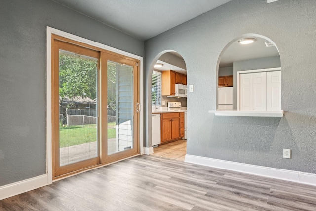 1509 Cedar Keys Dr, Lewisville, TX 75067 - doorway to outside with a textured wall, light wood-type flooring, baseboards, and arched walkways