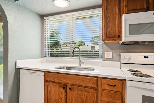 1509 Cedar Keys Dr, Lewisville, TX 75067 - kitchen with white appliances, a sink, a textured wall, arched walkways, and light countertops