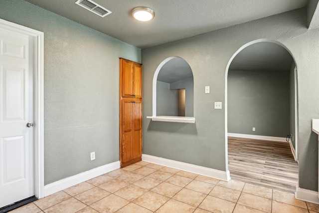 1509 Cedar Keys Dr, Lewisville, TX 75067 - spare room featuring light tile patterned floors, arched walkways, and baseboards