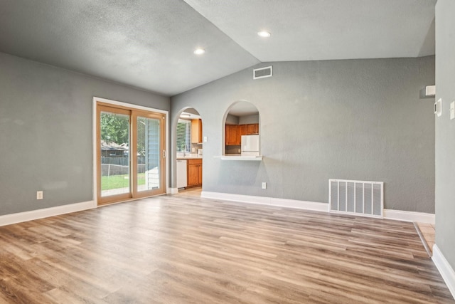 1509 Cedar Keys Dr, Lewisville, TX 75067 - unfurnished living room with light wood-type flooring, vaulted ceiling, baseboards, arched walkways, and recessed lighting