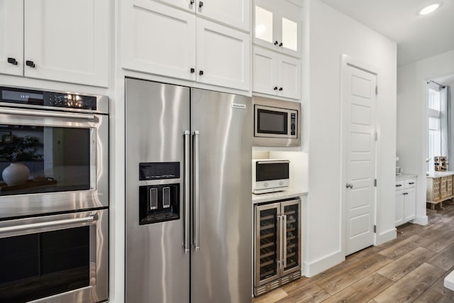 927 Leola Ln, Allen, TX 75013 - kitchen with appliances with stainless steel finishes, wine cooler, light wood-style flooring, white cabinets, and recessed lighting