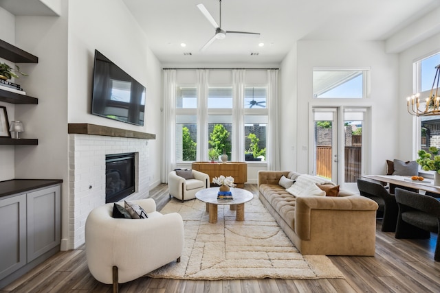 927 Leola Ln, Allen, TX 75013 - living area featuring a ceiling fan, wood finished floors, a fireplace, a chandelier, and a high ceiling