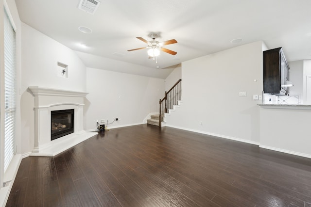 912 Kittery Dr, Desoto, TX 75115 - unfurnished living room with stairs, ceiling fan, a glass covered fireplace, dark wood finished floors, and baseboards