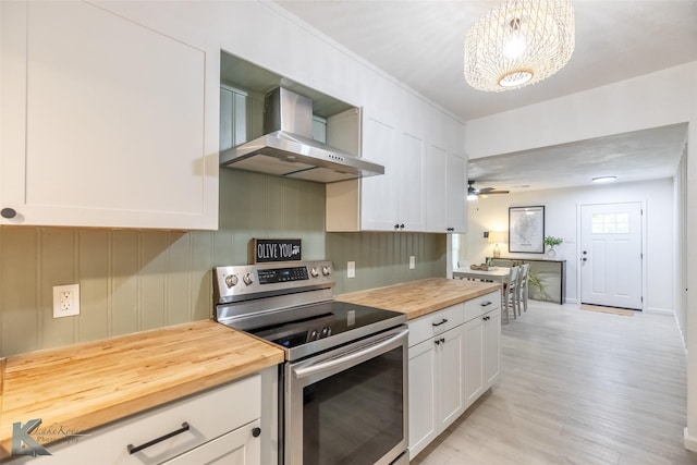 1518 Weavers Way, Abilene, TX 79602 - kitchen featuring stainless steel range with electric cooktop, wooden counters, wall chimney exhaust hood, white cabinets, and light wood finished floors