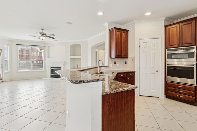 5723 Green Hollow Ln, The Colony, TX 75056 - kitchen with double oven, a peninsula, light tile patterned floors, a sink, and ceiling fan