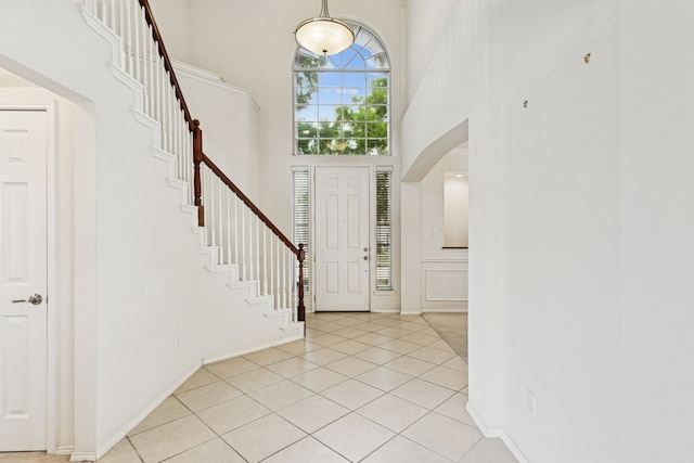 5723 Green Hollow Ln, The Colony, TX 75056 - entryway featuring a high ceiling, stairs, light tile patterned floors, arched walkways, and baseboards