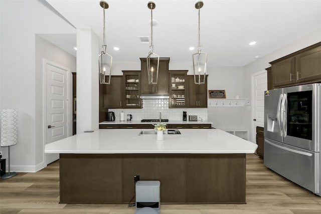 6329 Camey Place Way, The Colony, TX 75056 - kitchen featuring stainless steel fridge with ice dispenser, premium range hood, dark brown cabinetry, decorative backsplash, and light countertops