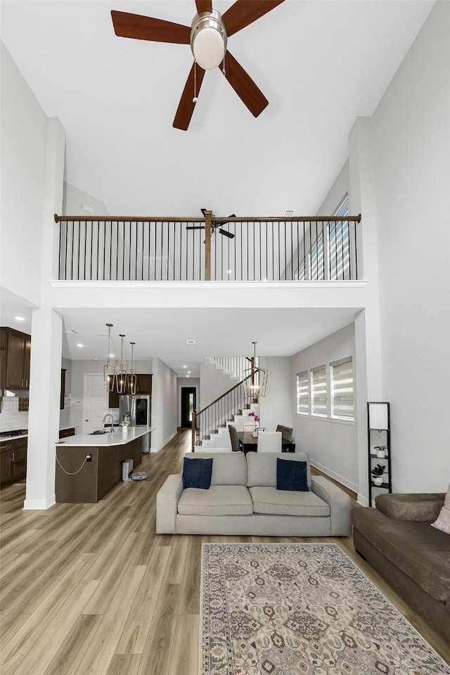 6329 Camey Place Way, The Colony, TX 75056 - living room with ceiling fan, light wood-style flooring, a high ceiling, and stairway