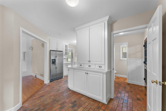 310 Northview Dr, Richardson, TX 75080 - kitchen with stainless steel fridge, brick flooring, white cabinets, baseboards, and light countertops