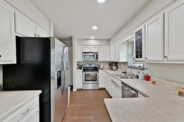 914 Glengarden St, Krum, TX 76249 - kitchen featuring appliances with stainless steel finishes, a sink, light wood-style floors, white cabinetry, and recessed lighting