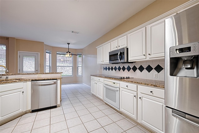 1503 Murphy Dr, Rockwall, TX 75087 - kitchen with stainless steel appliances, a sink, decorative backsplash, light tile patterned floors, and white cabinetry