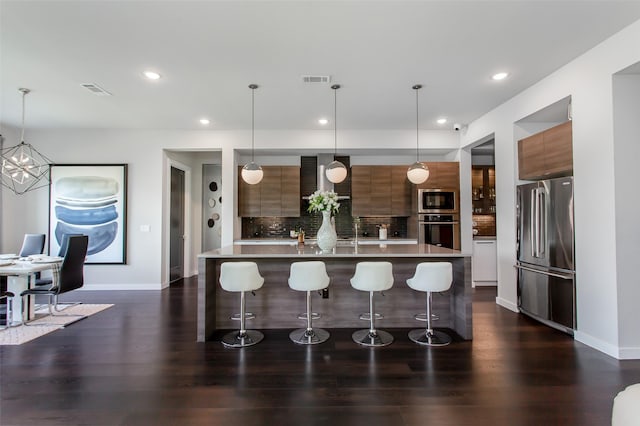 2468 Electra Dr, Allen, TX 75013 - kitchen with appliances with stainless steel finishes, modern cabinets, a kitchen bar, brown cabinets, and recessed lighting