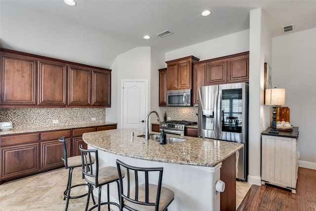1003 Stanbridge Dr, Wylie, TX 75098 - kitchen with appliances with stainless steel finishes, a sink, light stone counters, a center island with sink, and tasteful backsplash