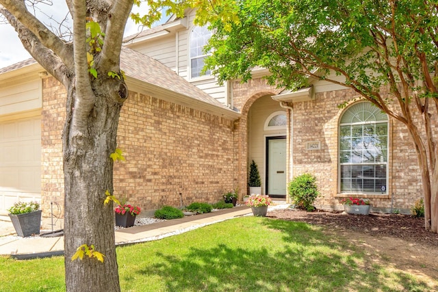 14221 Tijuana Trl, Fort Worth, TX 76052 - view of exterior entry with brick siding, a yard, and roof with shingles