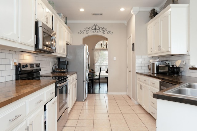 14221 Tijuana Trl, Fort Worth, TX 76052 - kitchen with stainless steel appliances, white cabinets, light tile patterned floors, backsplash, and crown molding