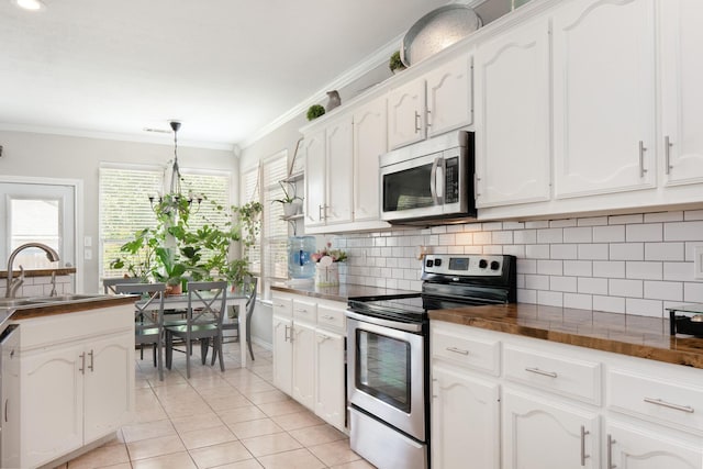 14221 Tijuana Trl, Fort Worth, TX 76052 - kitchen featuring appliances with stainless steel finishes, a sink, white cabinets, crown molding, and light tile patterned flooring