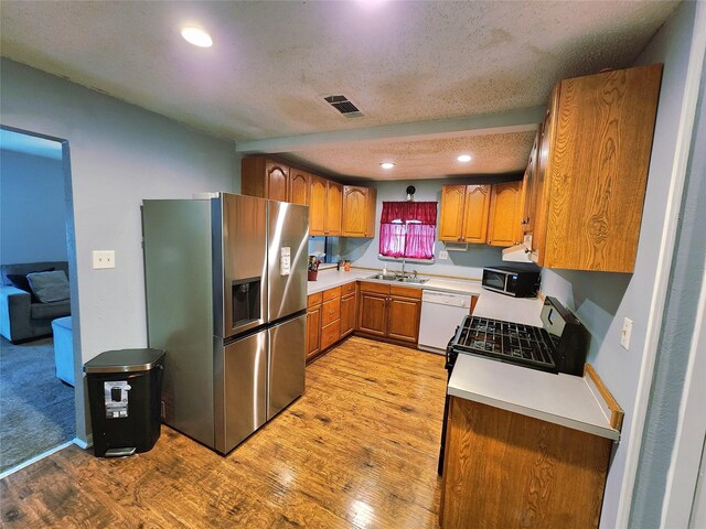 2908 Wilkinson Ave, Fort Worth, TX 76103 - kitchen with stainless steel fridge with ice dispenser, a sink, light wood finished floors, brown cabinets, and dishwasher