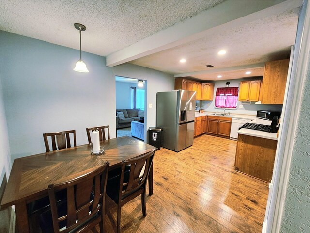2908 Wilkinson Ave, Fort Worth, TX 76103 - kitchen featuring stainless steel refrigerator with ice dispenser, white dishwasher, a sink, a textured ceiling, and light wood-type flooring