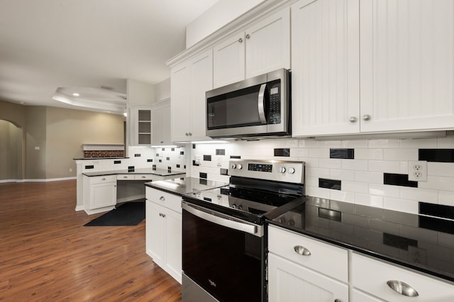 6345 Pinionpark Way, Fort Worth, TX 76179 - kitchen featuring appliances with stainless steel finishes, arched walkways, backsplash, dark countertops, and dark wood-style flooring