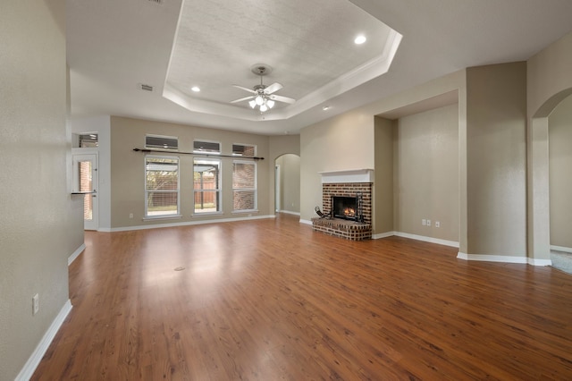 6345 Pinionpark Way, Fort Worth, TX 76179 - unfurnished living room with a tray ceiling, wood finished floors, ceiling fan, arched walkways, and a fireplace