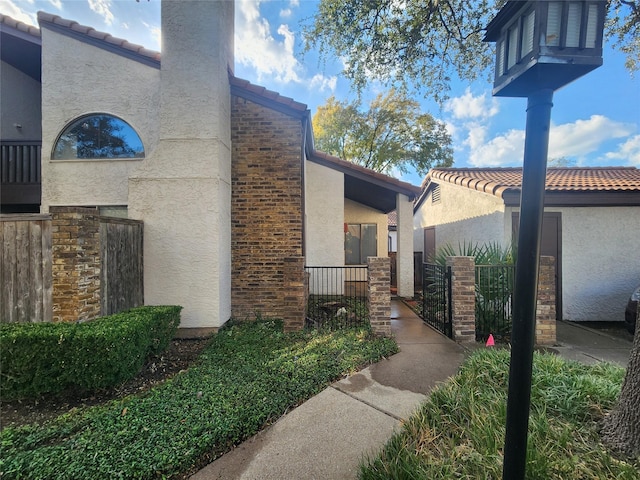 18040 Midway Rd Unit 123, Dallas, TX 75287 - view of side of property with stucco siding, a tile roof, and a gate