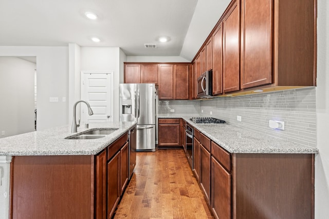 2212 Kingfisher St, Crandall, TX 75114 - kitchen with a sink, appliances with stainless steel finishes, wood finished floors, light stone counters, and a center island with sink